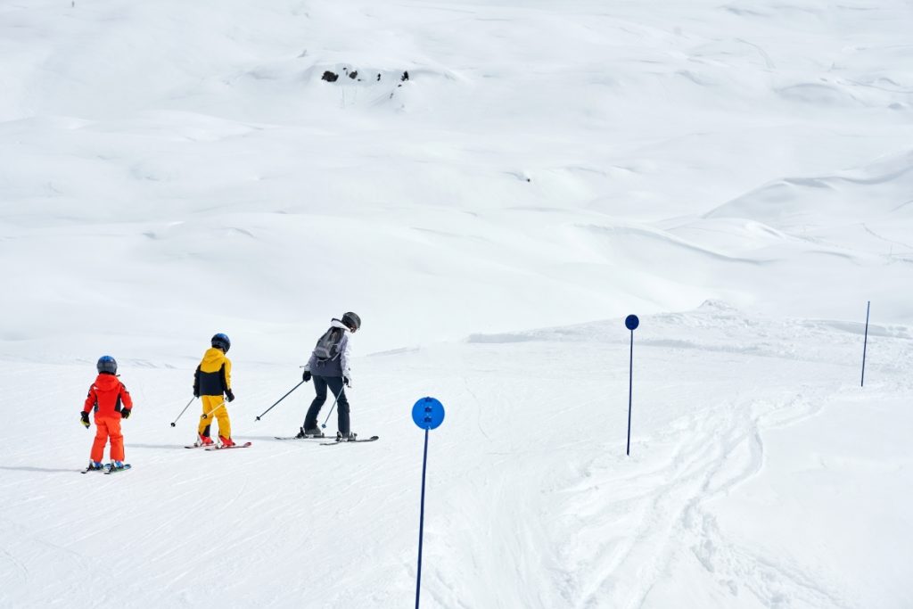 A mother teaching skiing her kids to ski in Madonna di Campiglio, Italy. Image Kamil Macniak Shutterstock