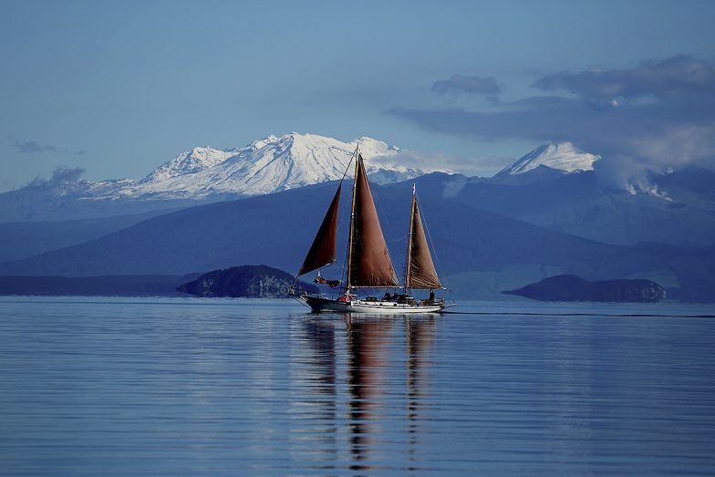Sailing Lake Taupo with mountains in background e1638388724443