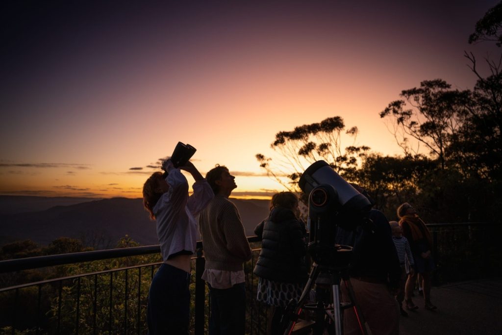 Family enjoying a Blue Mountains Stargazing activity as the sun sets. Image Destination NSW