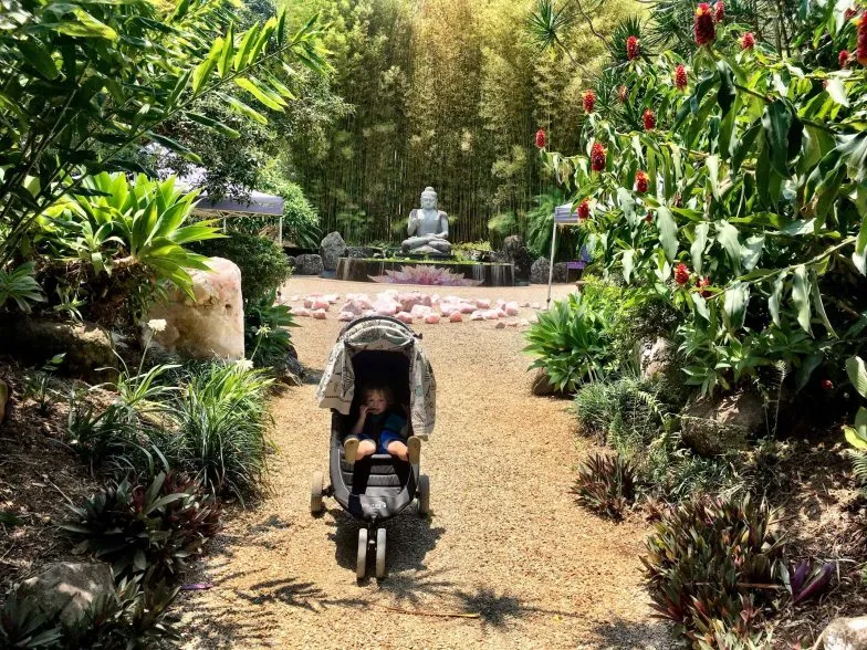 Oliver in front of a Buddha statue at Crystal Castle in the Byron Bay hinterland