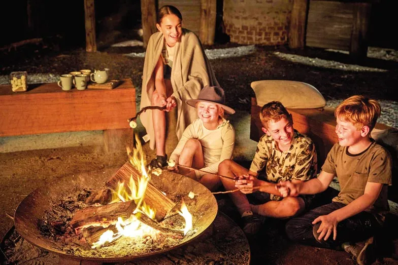 Kids sitting around the fire pit at Paperbark Camp