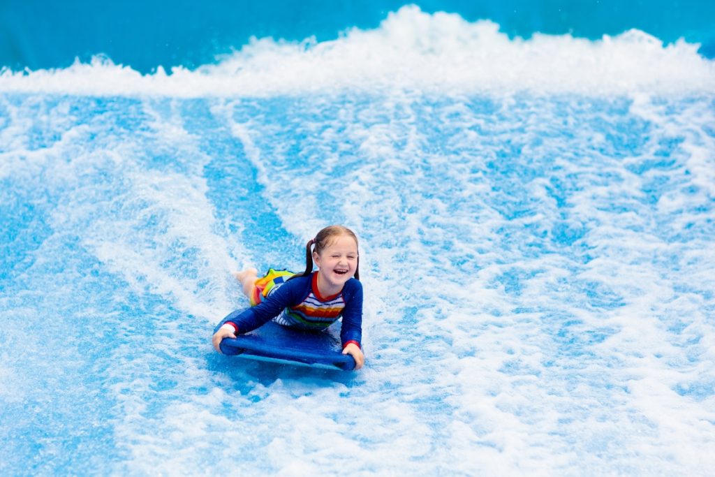 Little girl riding surf simulator on a boogie board
