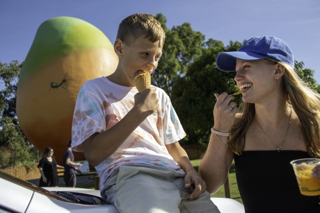 Kids enjoy a sweet treat in front of Bowen's famous Big Mango. Image Tourism and Events Queensland