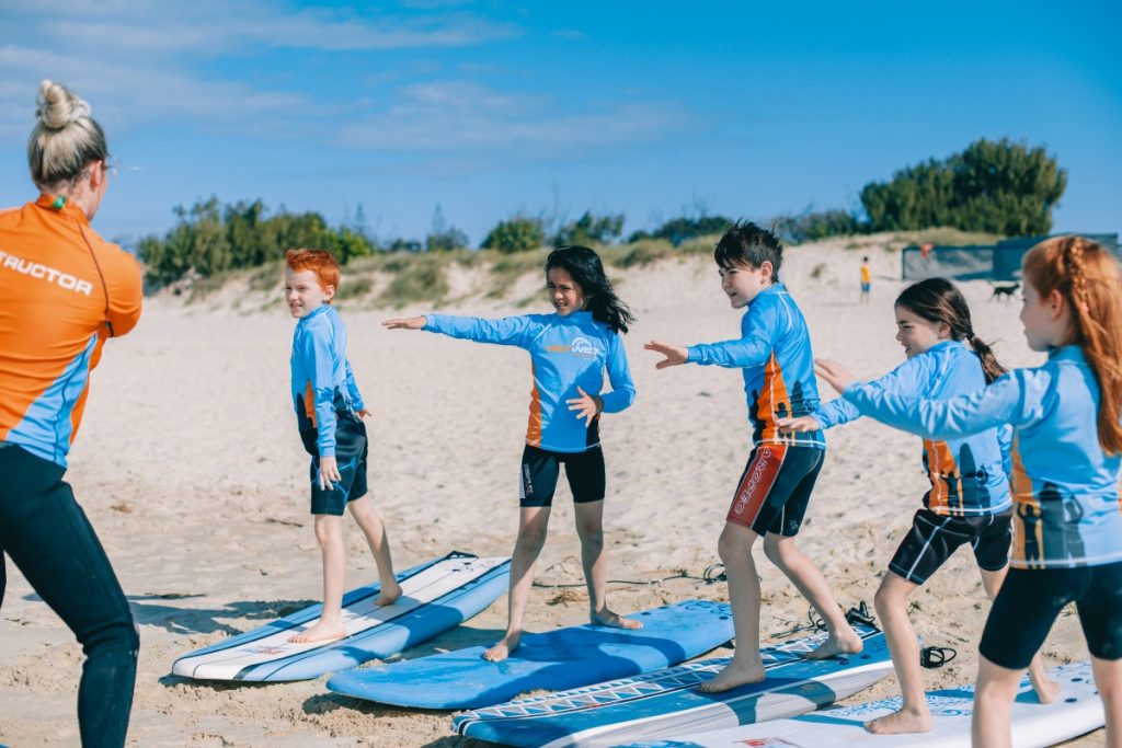 A group of kids learning to surf with Get Wet Surf School. Image Experience Gold Coast