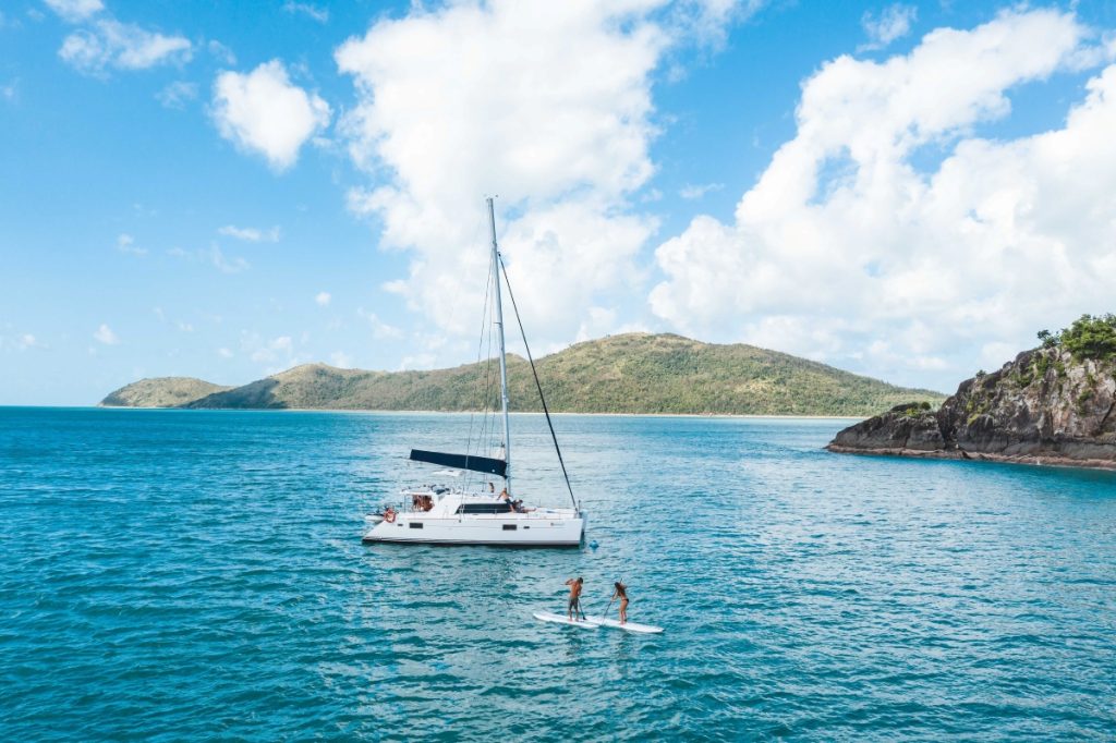Family sailing and paddleboarding in the Whitsunday Islands. Image Tourism Whitsundays