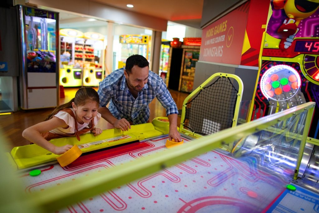 Father and daughter playing air hockey game at Timezone Surfers Paradise. Image Experience Gold Coast