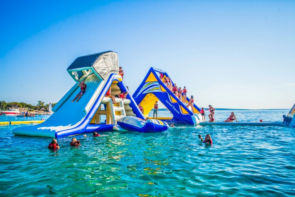 Families and kids enjoying the inflatable obstacle course at GC Aqua Park off Broadwater Parklands. Image Experience Gold Coast