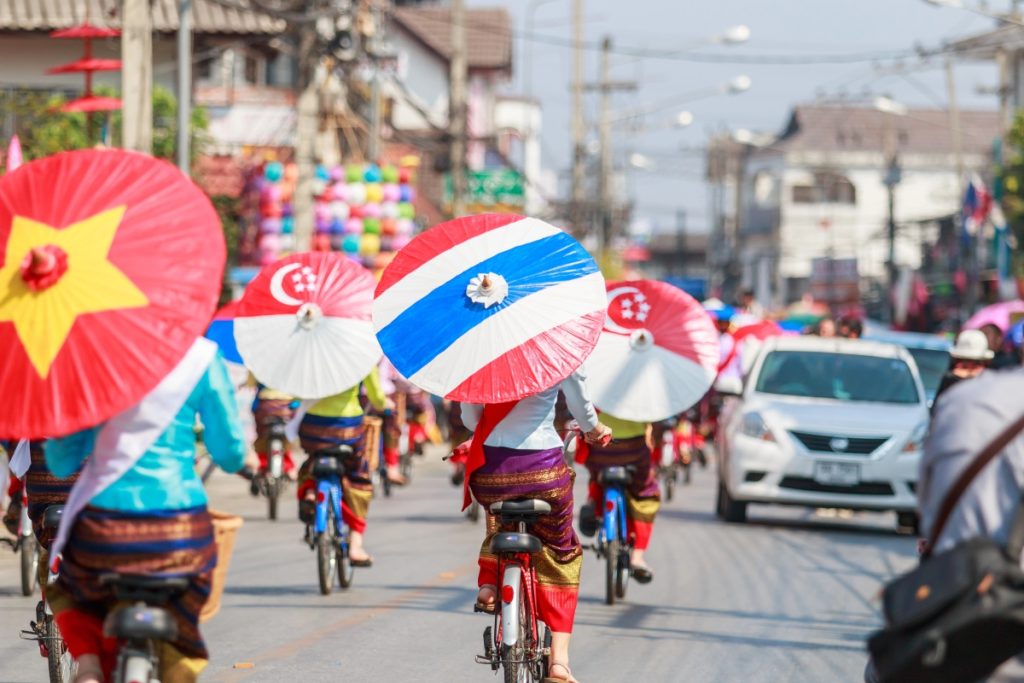 Women ride bikes with colourful umbrellas during the annual Umbrella Festival in Bo Sang, Thailand. Image Deerphoto Depositphotos